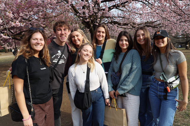student in front of cherry blossom.