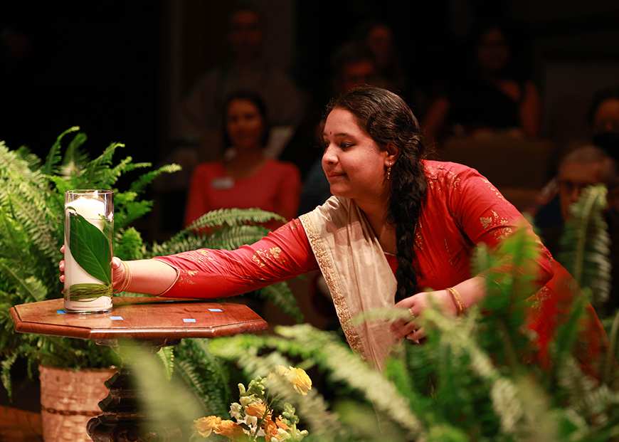 Representing the Hindu faith, USD student Shree Narasimhan picks up a candle during the concluding procession of the 30th All Faith Service in the KIPJ Theatre on Thurs., Feb. 9, 2023. (Photo by Matthew Piechalak)