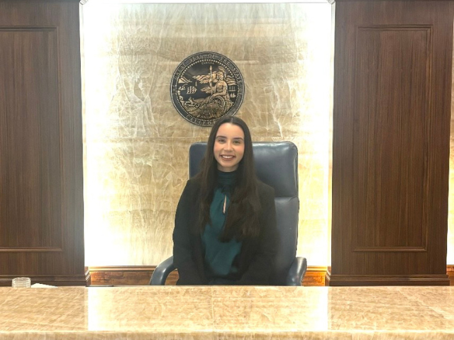 Reese O'Driscoll sitting in front of a state of California seal.