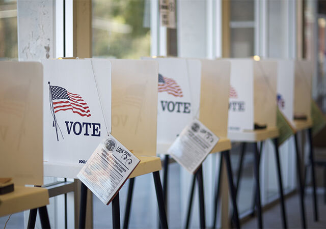 ballot cubicles with white flyers on them that show the American flag alongside the word Vote