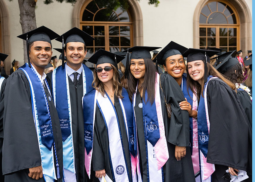 A group of graduates from the College of Arts and Sciences smile for a photo after commencement outside the Jenny Craig Pavilion (JCP) on Sunday, May 26, 2024. (Photo by Zachary Barron)