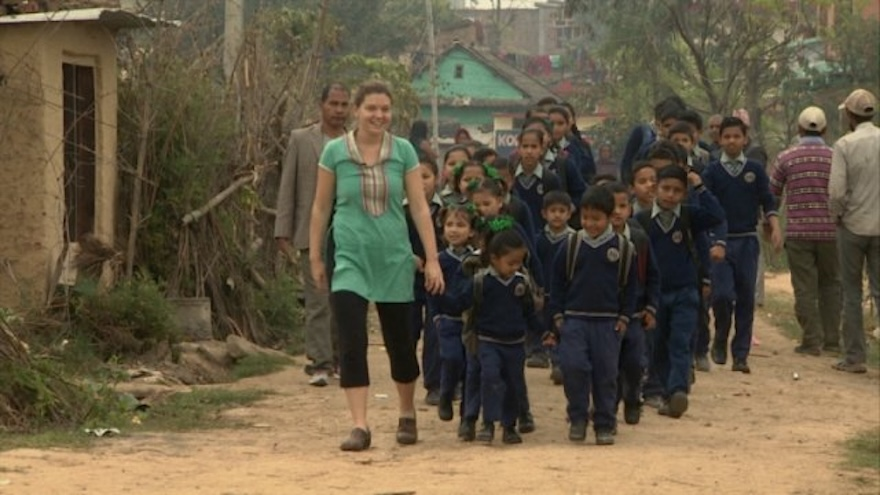 Maggie Doyne leading a group of school children down the street. in Nepal