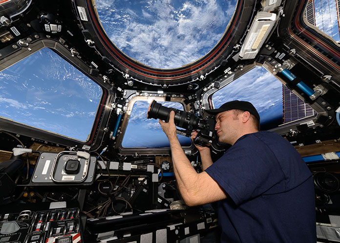 NASA Astronaut Matthew Dominick ’05 (BS/BA) looks through the viewfinder of his camera while capturing images aboard the International Space Station in 2024. Dominick spent 235 days in space and shot more than 500,000 photos.