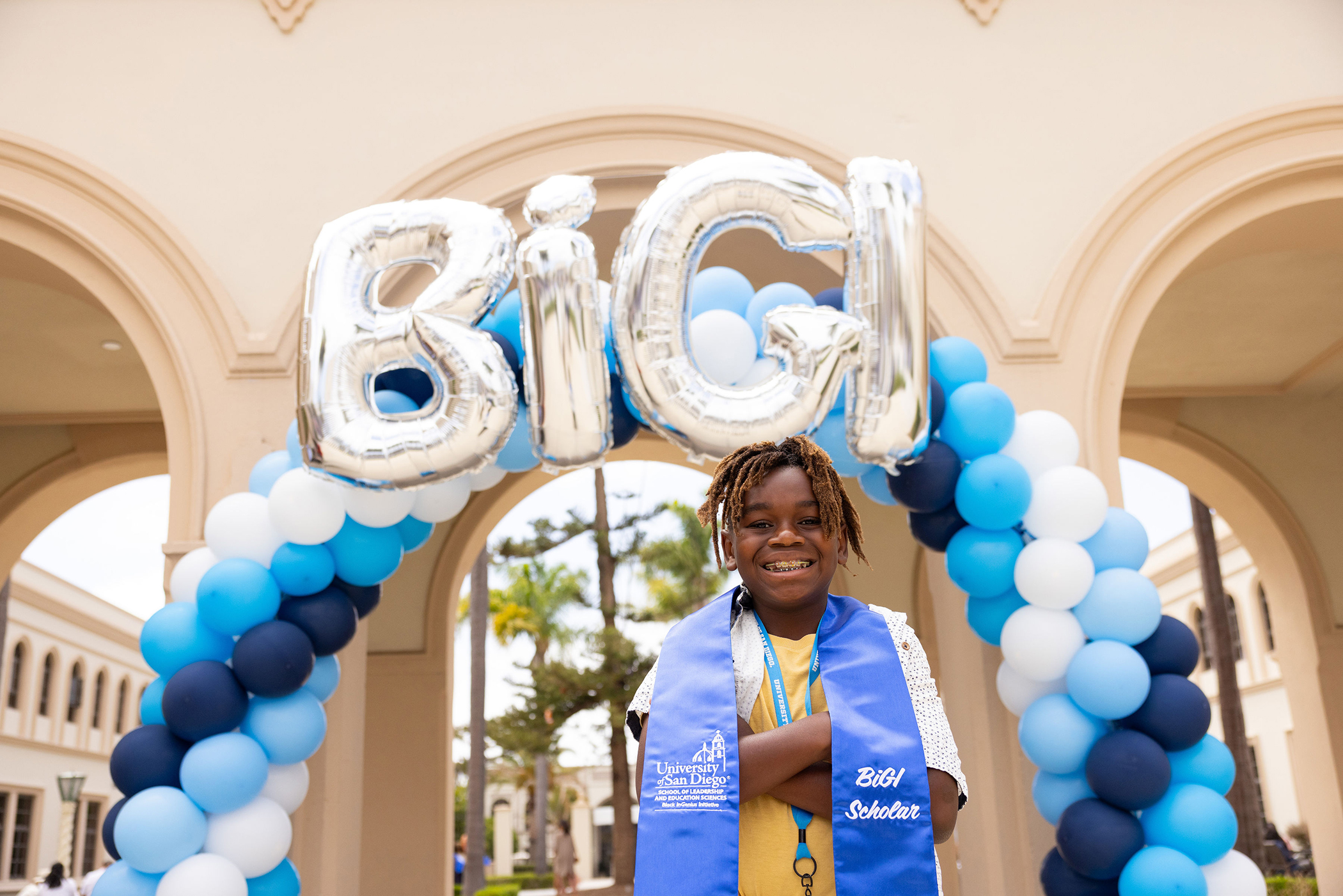 BiGI scholar standing in front of BiGI balloon arch