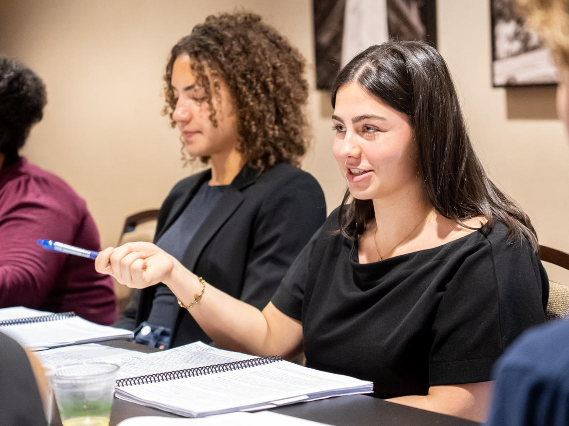 A student holding a pen and gesturing as she's talking during the 2026 PPE Colloquium.
