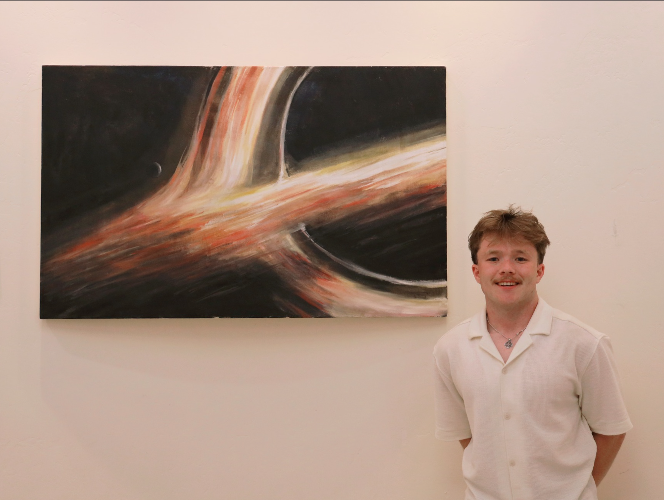 Lucan Rhatigan stands with his painting of a black hole on canvas. 