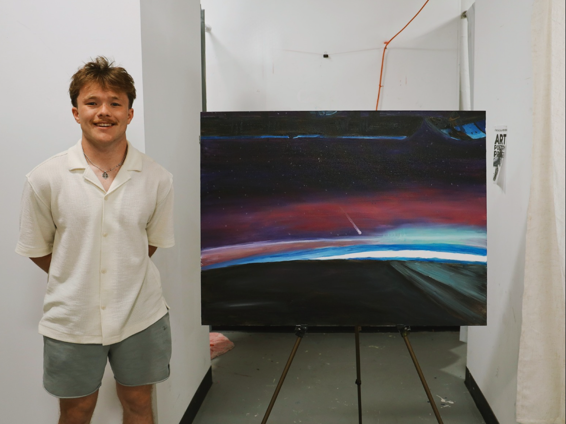 Lucan Rhatigan stands with his painting of an aurora on canvas.