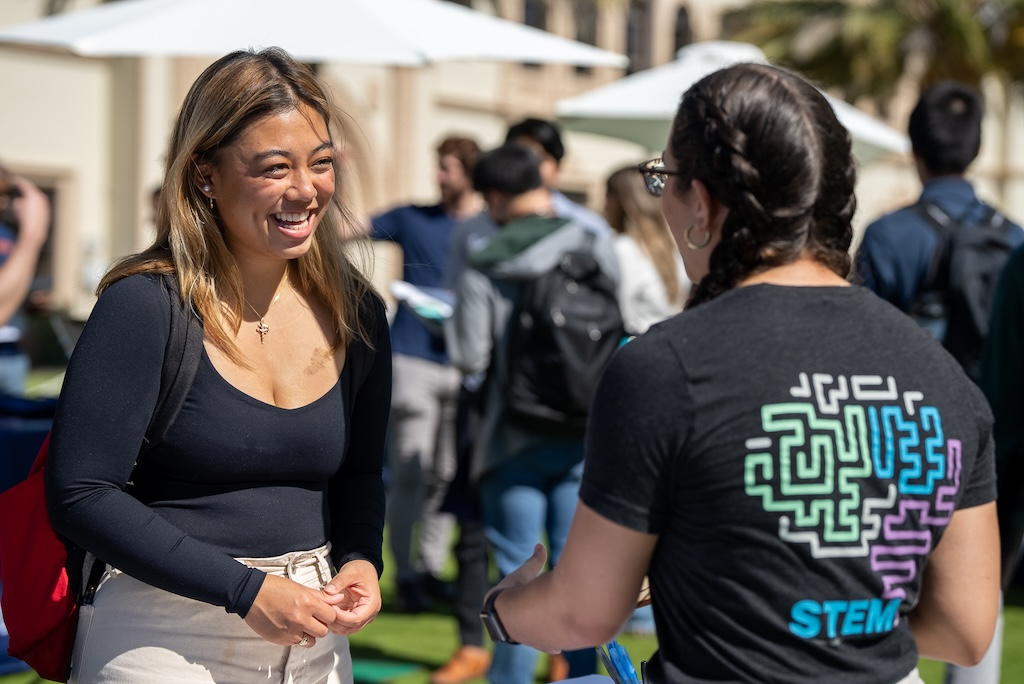 Two USD students are talking and smiling at each other on campus.