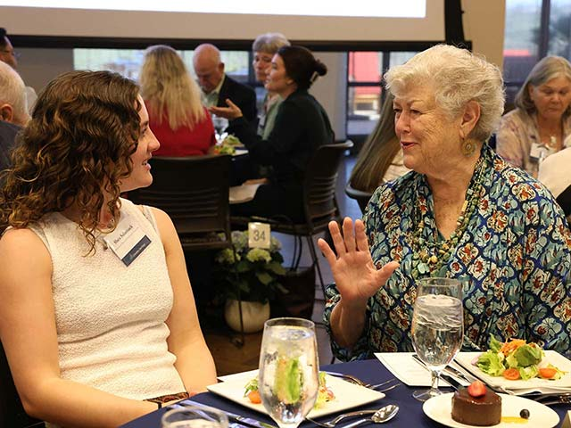 Student and donor speaking at luncheon event.