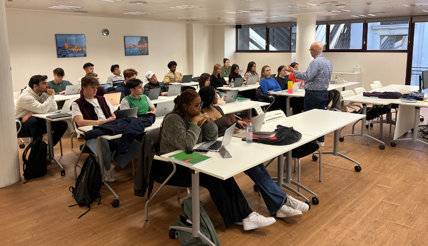 A faculty member stands in front of a classroom of students in the current Madrid Center.
