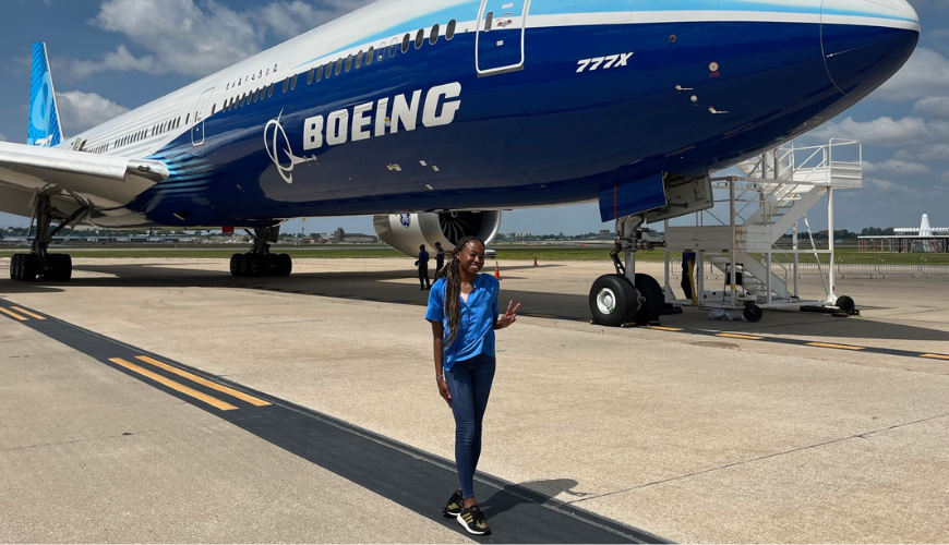 Shiley-Marcos School of Engineering student Aliyah Jones stands on a tarmac in front of The Boeing Company's 777X.