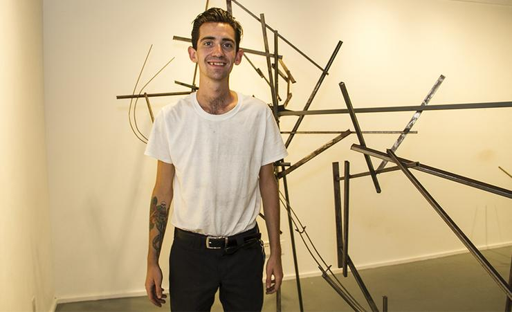 Stanley Ryan, a junior in the Department of Art, Architecture and Art History, stands in front of part of his "Crash" exhibit that he worked on this summer with a SURE grant from the university.