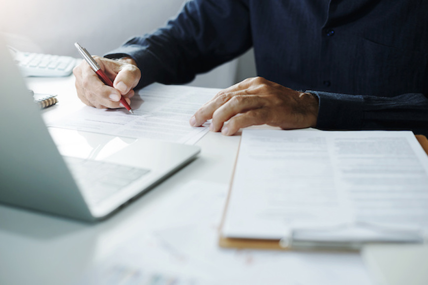 A businessperson sitting at a desk and signing a paper.
